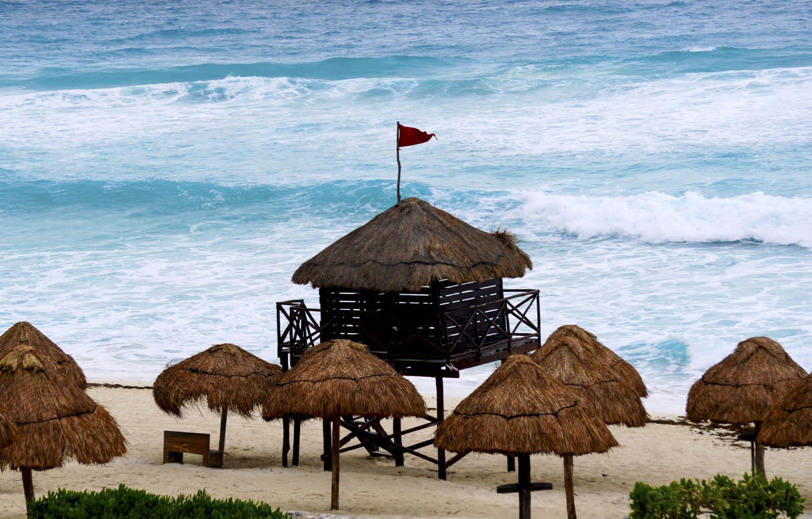 Un drapeau rouge est visible au sommet d’un poste de sauveteur sur une plage avant l’arrivée de l’ouragan Béryl à Cancún. Les stations touristiques de la péninsule du Yucatán au Mexique ont été cernées jeudi pour le coup de l’ouragan Béryl.