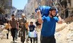 Un Palestinien transporte un réservoir de gaz à travers les ruines de Khan Younès, mercredi.