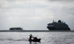 Un homme pagaie près de l’île de Gardi Sugdub où flotte un bateau de croisière dans l’archipel des San Blas, au large de la côte caraïbe du Panama, dimanche 26 mai 2024.