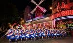 Des danseurs se produisent devant le cabaret du Moulin Rouge lors de l’inauguration des voiles du moulin à vent du théâtre à Paris le 5 juillet 2024.